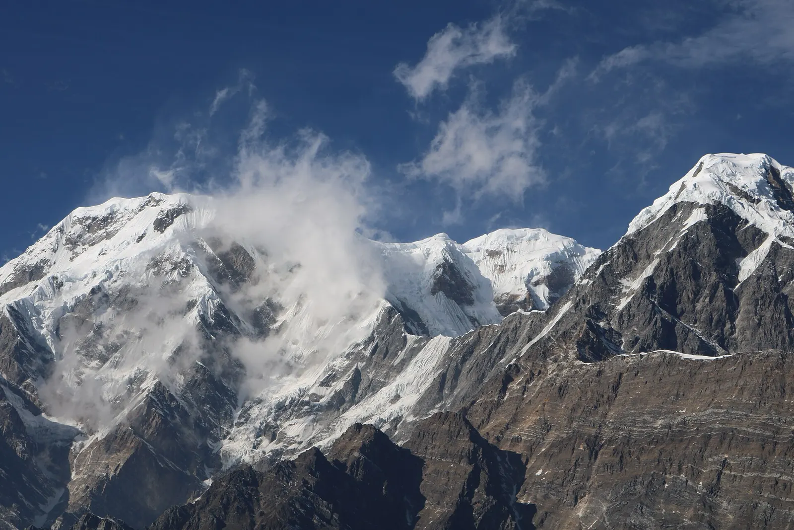 Snow-covered peaks of the Annapurna range with clouds drifting across the ridges, seen from the Mardi Himal trail