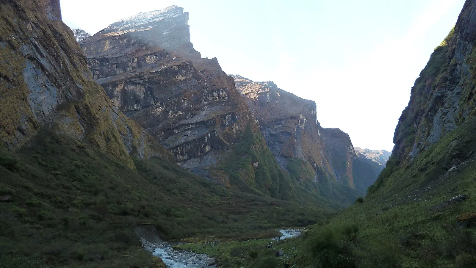 Steep rock walls and grassy slopes enclosing the upper Modi Khola valley on the way into the Annapurna Sanctuary.