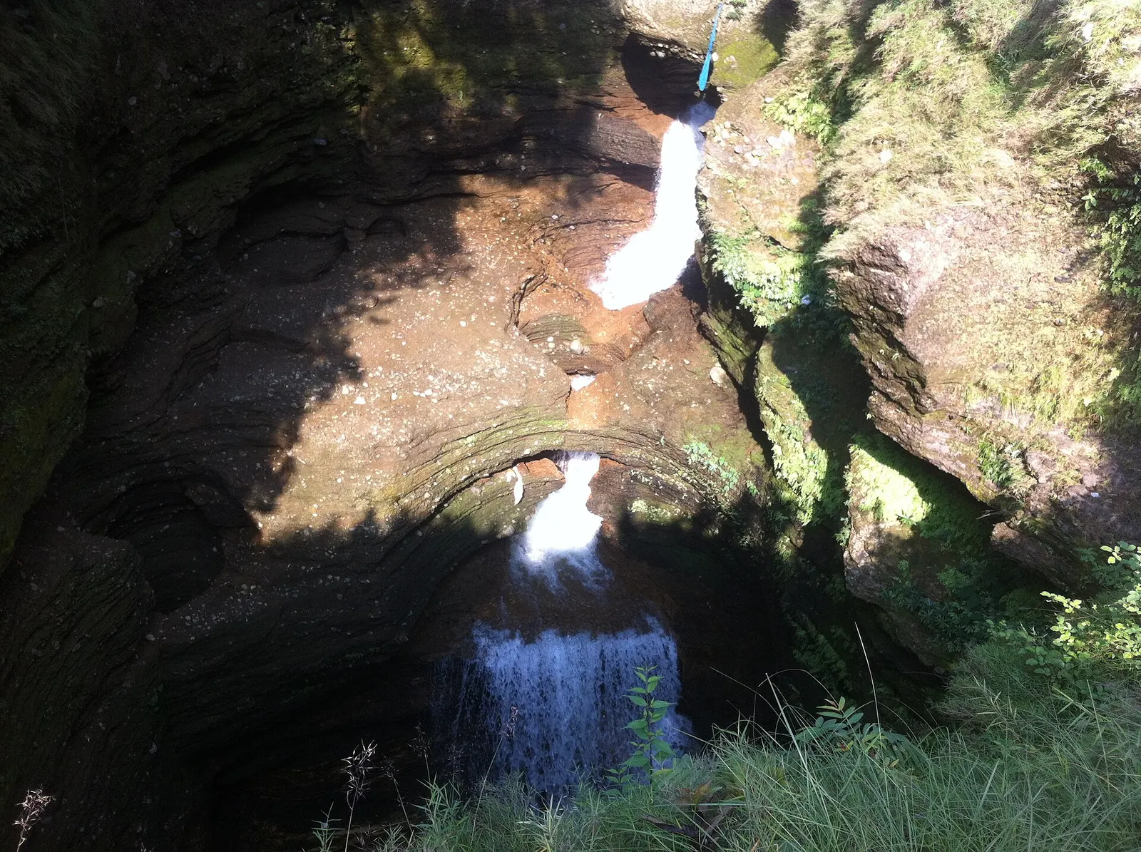 Water dropping through a narrow, moss-covered rock channel at Davis Falls before it disappears underground.