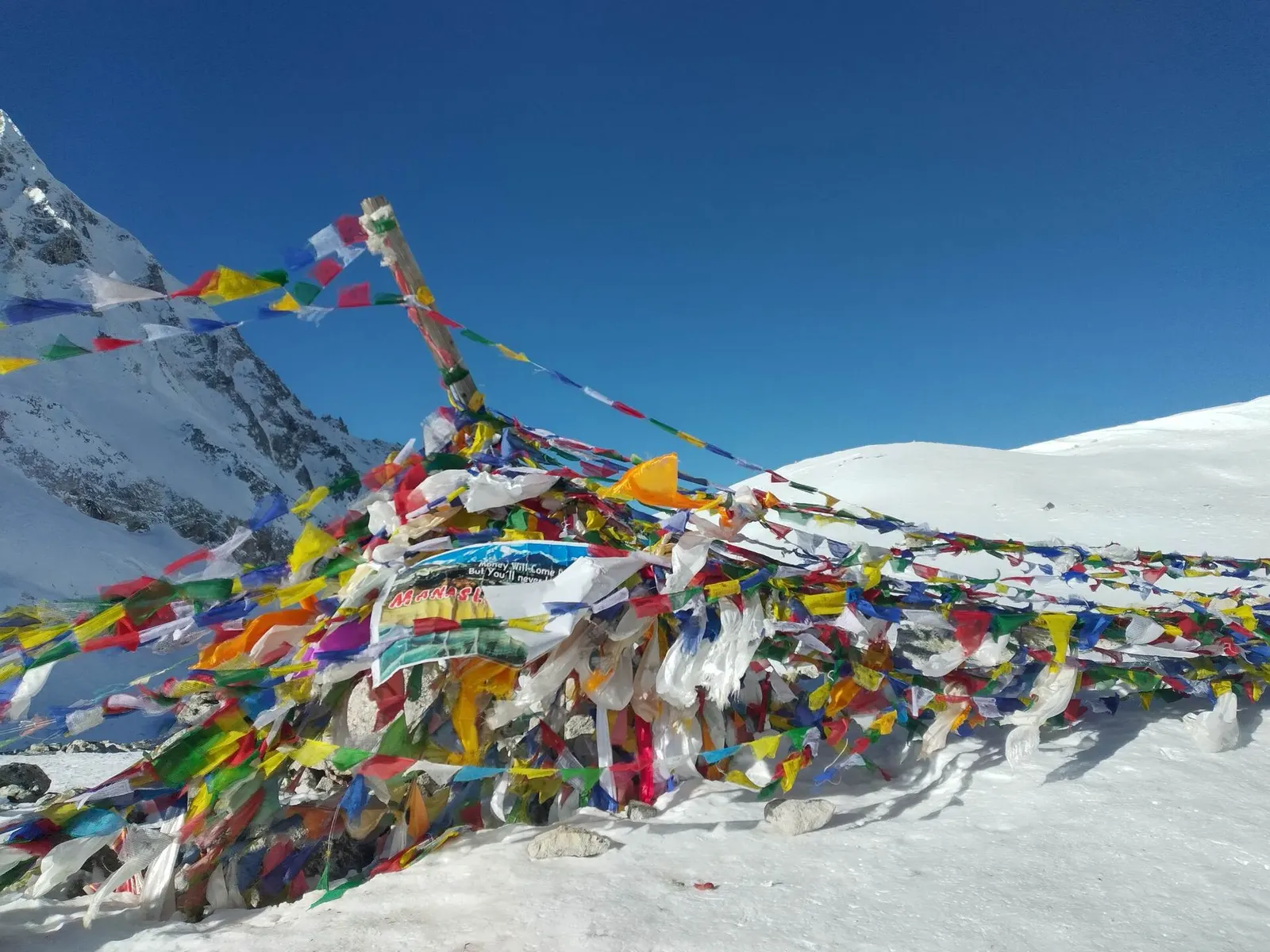 Prayer flags at the Larkya La pass with snow peaks around it.