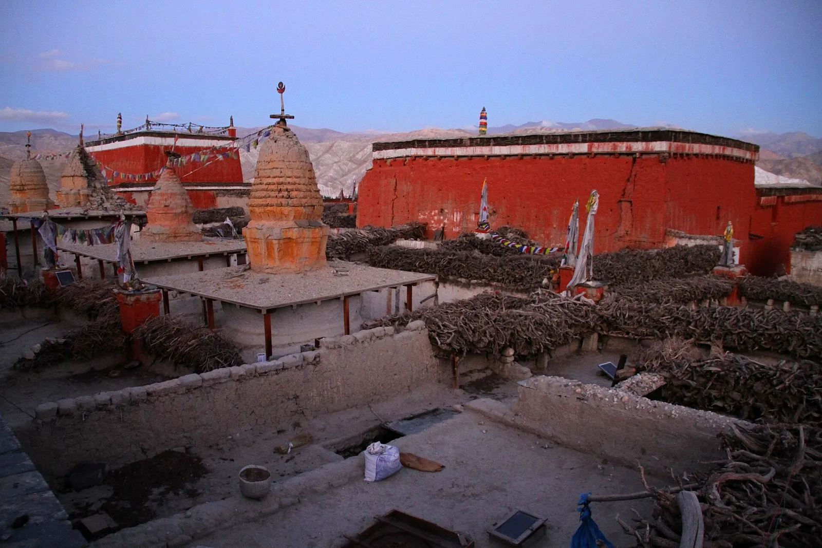 Rooftops of Lo Manthang stacked with firewood, with the surrounding hills behind.