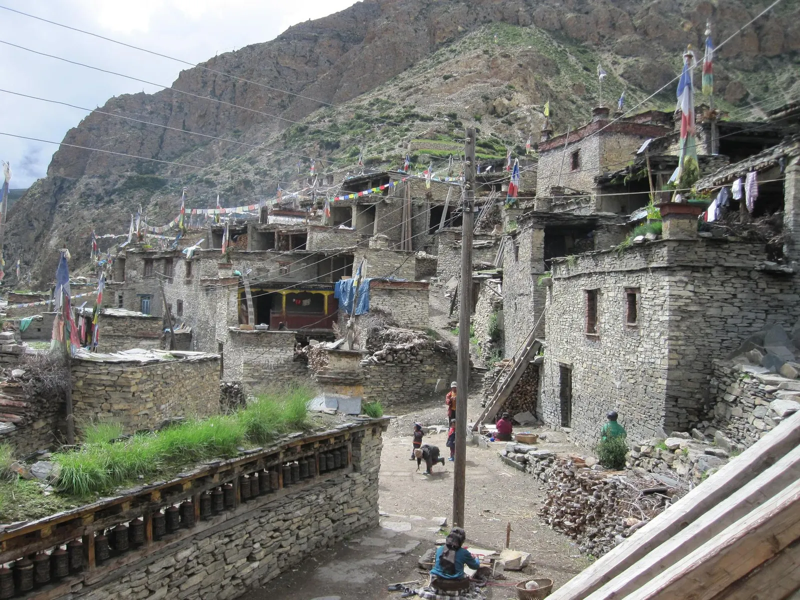 Stone houses, prayer flags and a row of prayer wheels in Nar village.