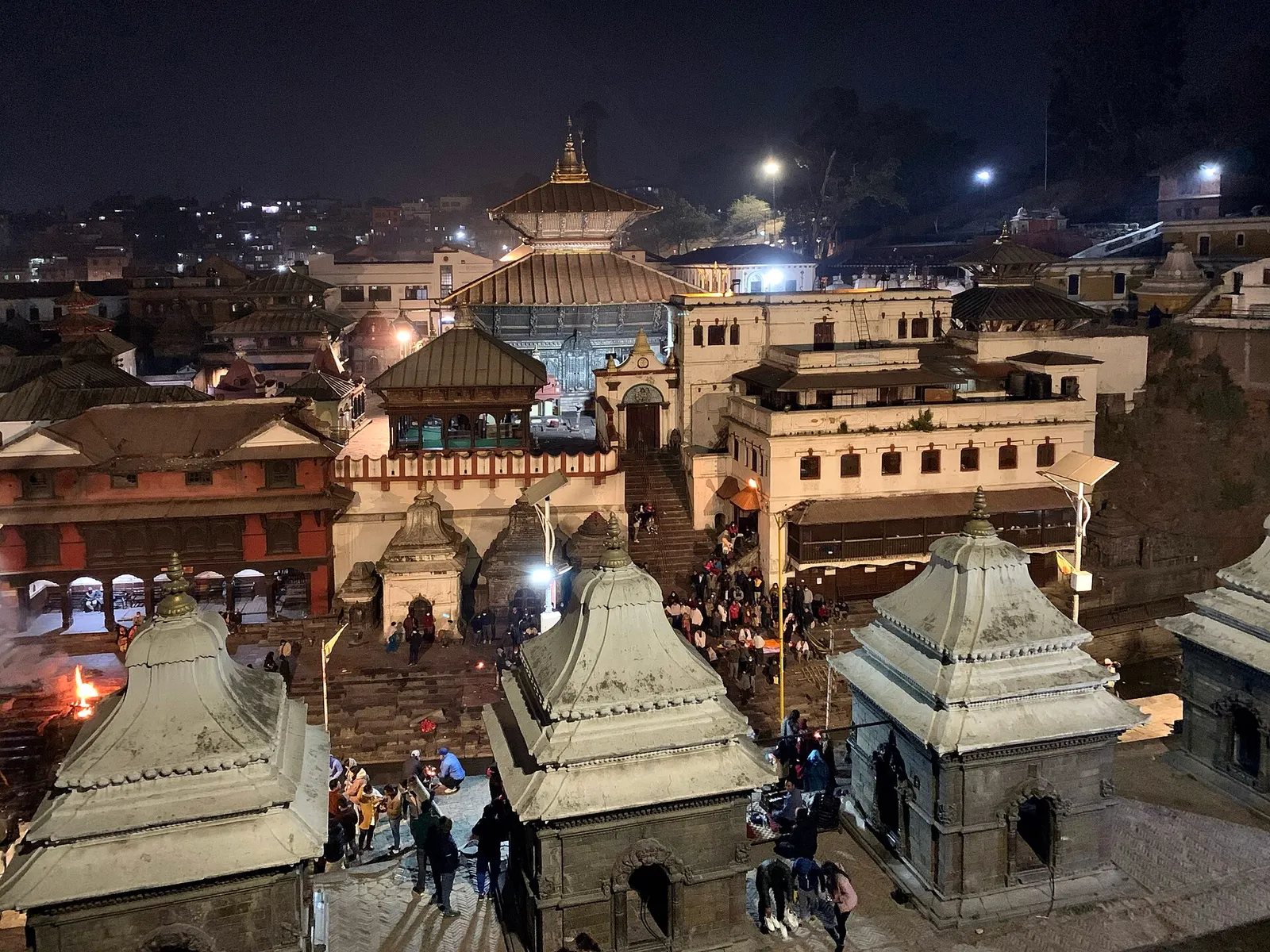 Evening aarti on the banks of the Bagmati river at Pashupatinath Temple, lit by lamps.