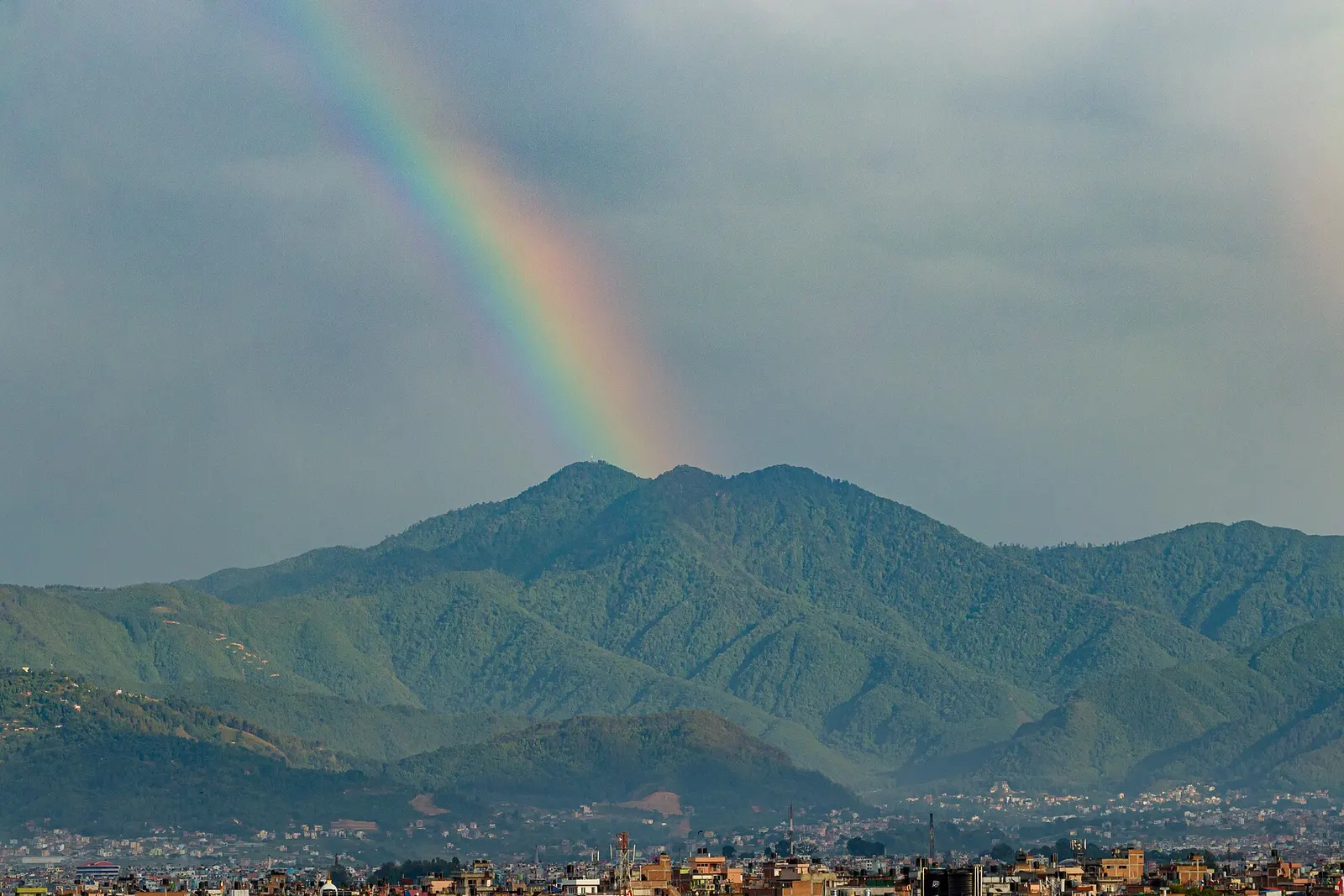 Phulchowki hill on the southern rim of the Kathmandu Valley with a rainbow in front.