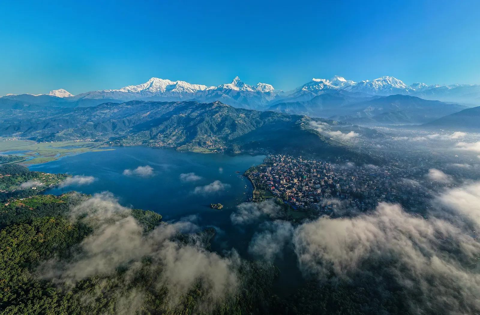 Morning view over Pokhara with Phewa Lake, the city under low cloud and the Annapurna range on the skyline.