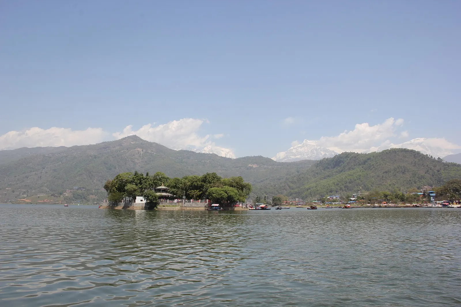 The tree-covered Tal Barahi island sitting low on Phewa Lake with green hills behind.
