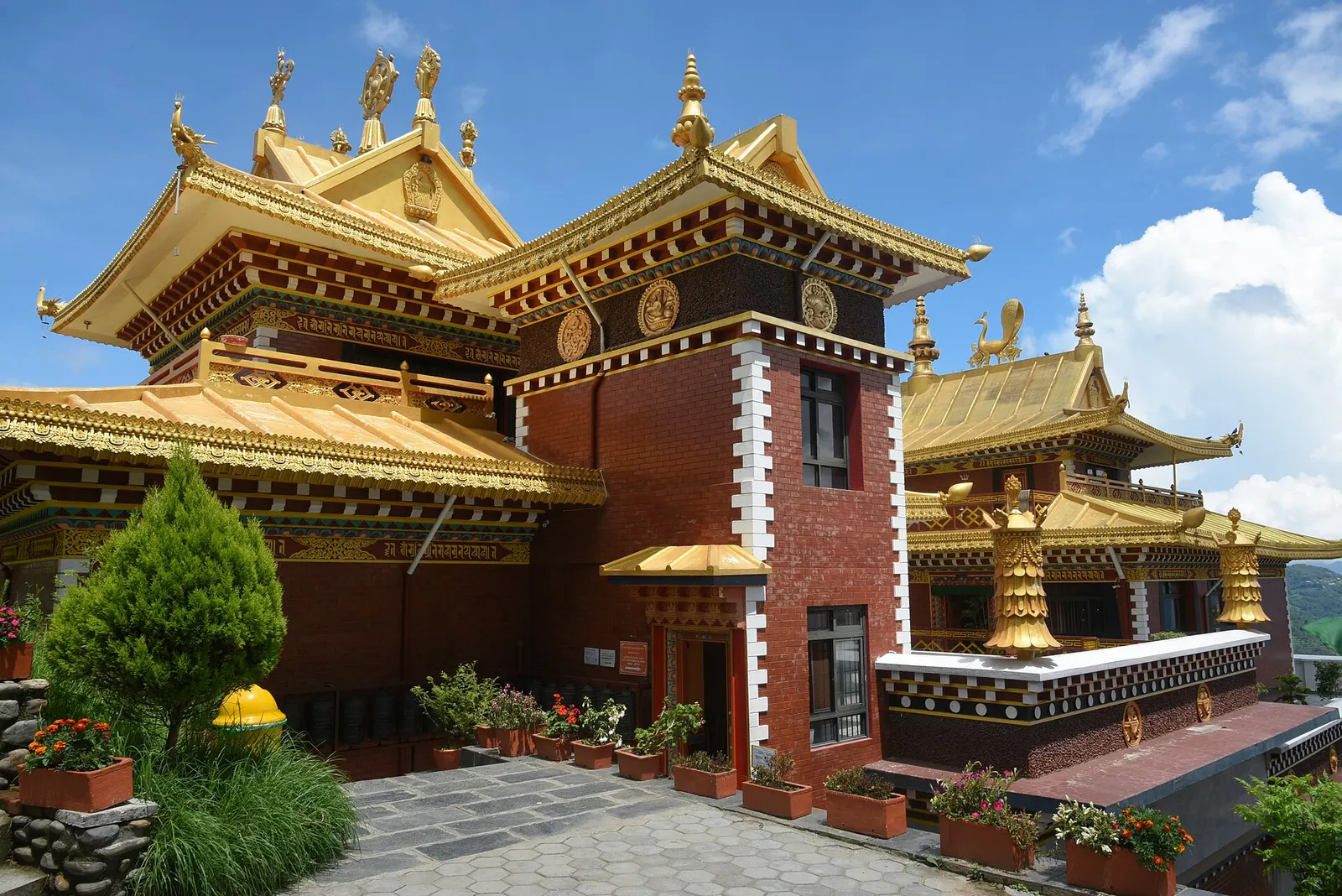 The monastery at Namo Buddha with its gold roofs on a forested ridge.