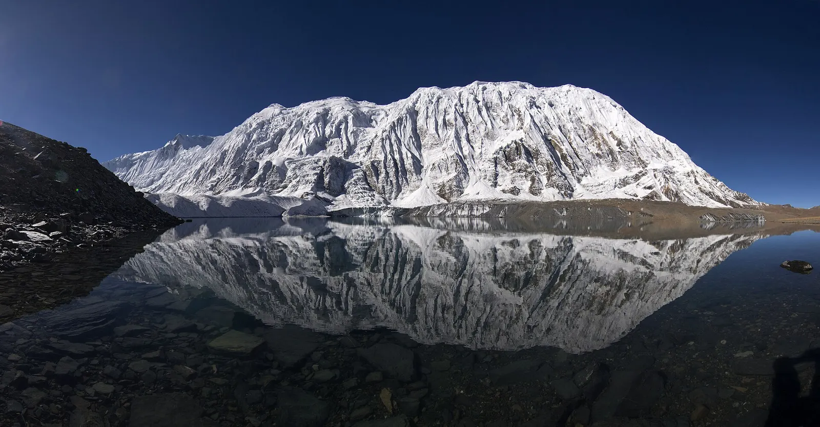 Tilicho Lake with Tilicho Peak reflected in the water.